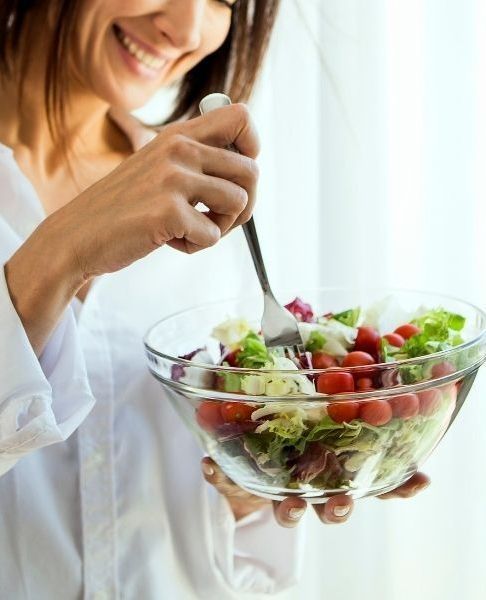 Pessoa sorrindo desfrutando uma refeição saudável com alegria e vitalidade