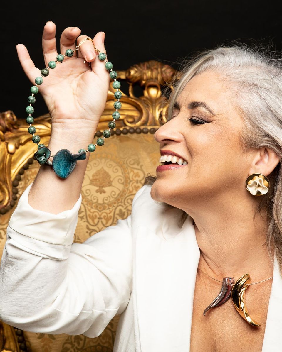 Márcia Campetti sorrindo em seu ateliê de cerâmica